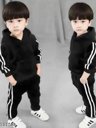A pair of young children modeling a matching black tracksuit set with white double stripes on the sleeves and pants, wearing white athletic sneakers